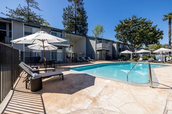 A swimming pool with chairs and umbrellas next to a building